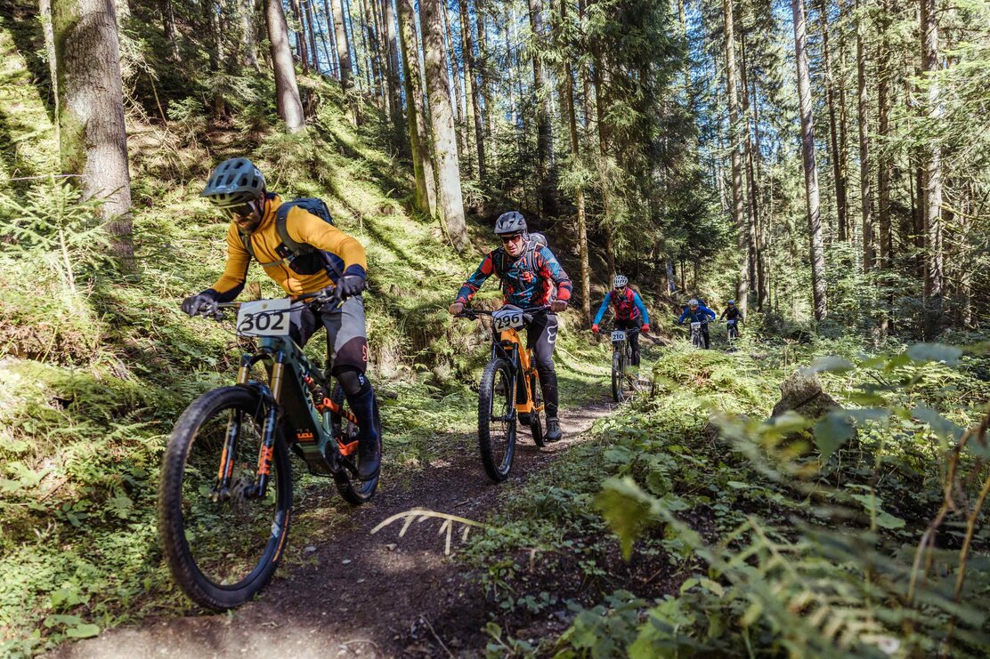 Fünf Männer fahren mit ihrem E-Bikes hintereinander einen schmalen Waldweg bergauf, sie sind Teilnehmer des  E-Bike Battles in Reith i.A.  | © Alpbachtal Tourismus | shootandstyle 