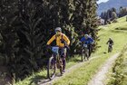 E-Bike Battle Reith i.A. | © Alpbachtal Tourismus | shootandstyle Zwei Männer sowie eine Frau, bewegen sich mit ihren E-Bikes bergauf, einer Forststraße entlang, sie sind alle Teilnehmer des E-Bike Battles | © Alpbachtal Tourismus | shootandstyle