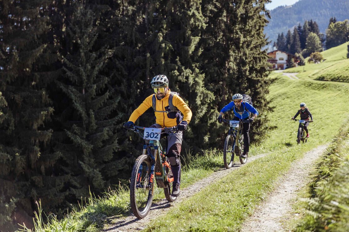 Zwei Männer sowie eine Frau, bewegen sich mit ihren E-Bikes bergauf, einer Forststraße entlang, sie sind alle Teilnehmer des E-Bike Battles  | © Alpbachtal Tourismus | shootandstyle 
