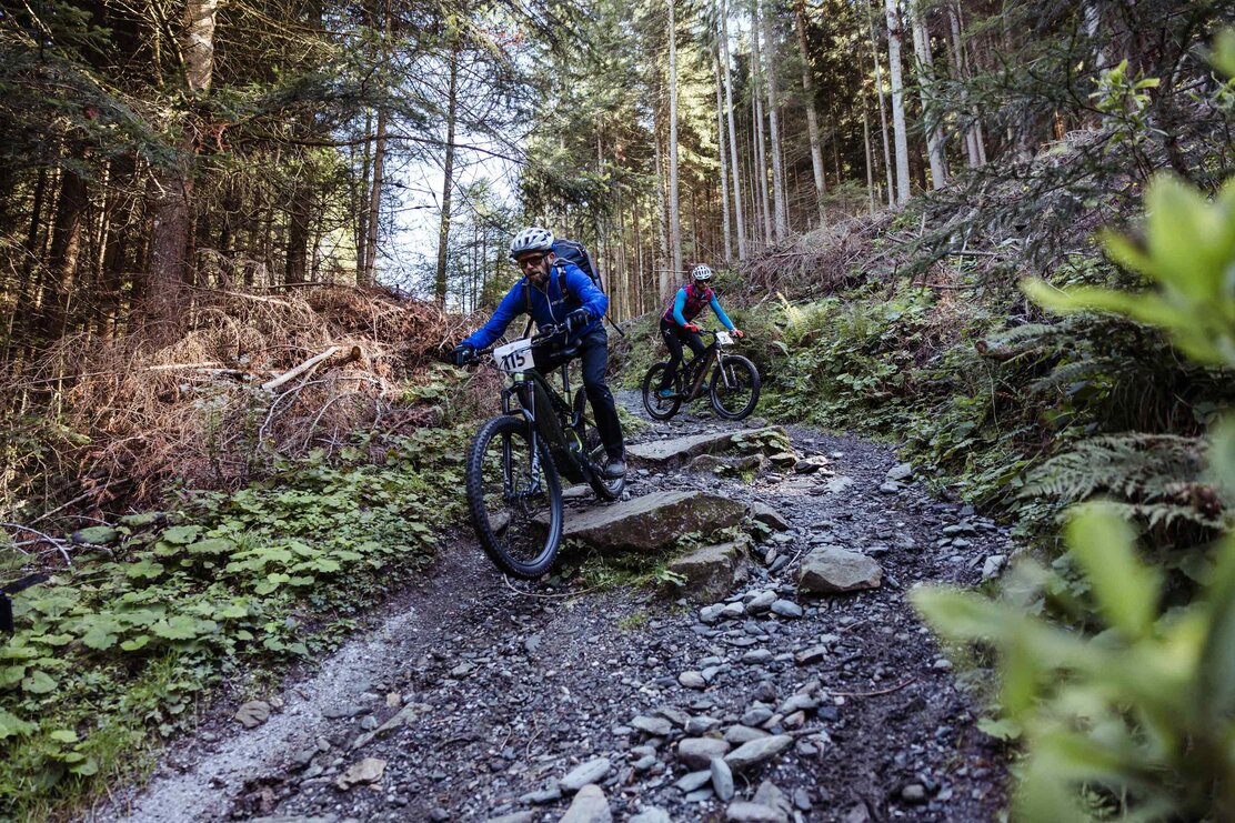 Zwei Teilnehmer des Reither E-Bike Battles rasen einem steinigen Weg entlang, in Richtung Tal und Ziel  | © Alpbachtal Tourismus | shootandstyle 